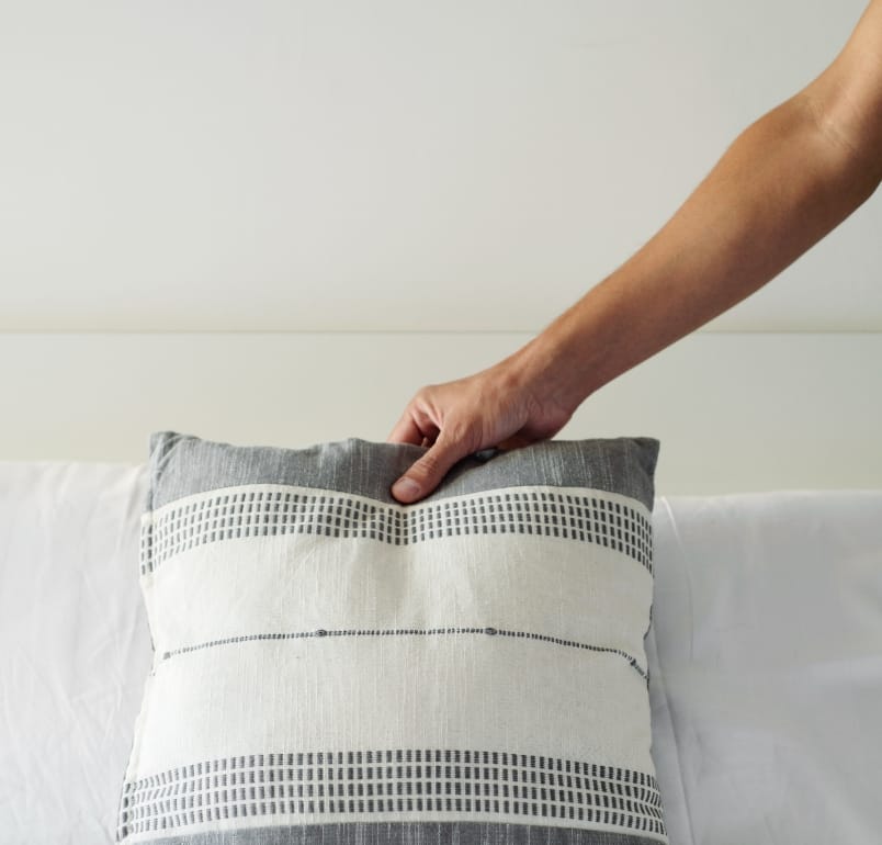 A member of the dedicated residence team places a decorative pillow on a freshly made bed spread